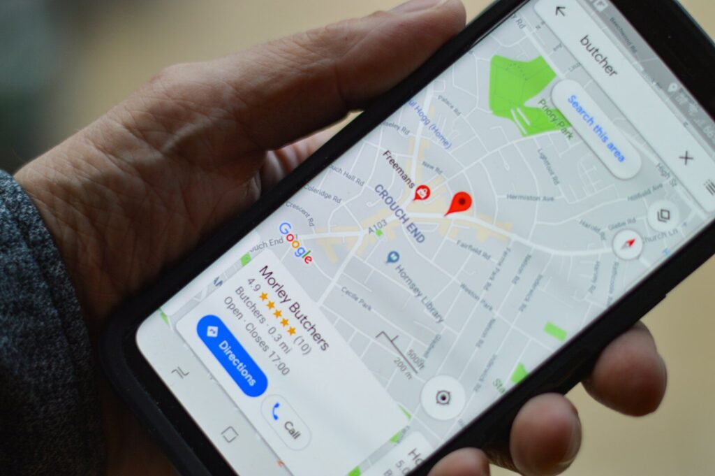 Dłoń trzymająca telefon z otwartą mapą i zaznaczonymi miejscami w okolicy