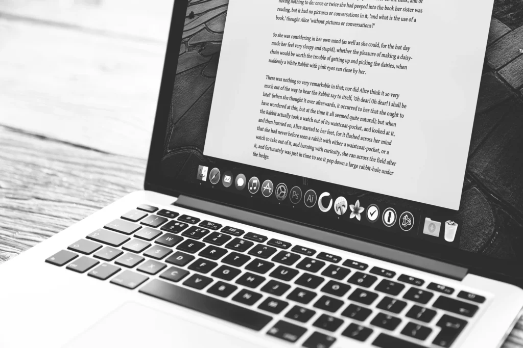 Laptop z otwartym dokumentem tekstowym na ekranie, zdjęcie czarno-białe