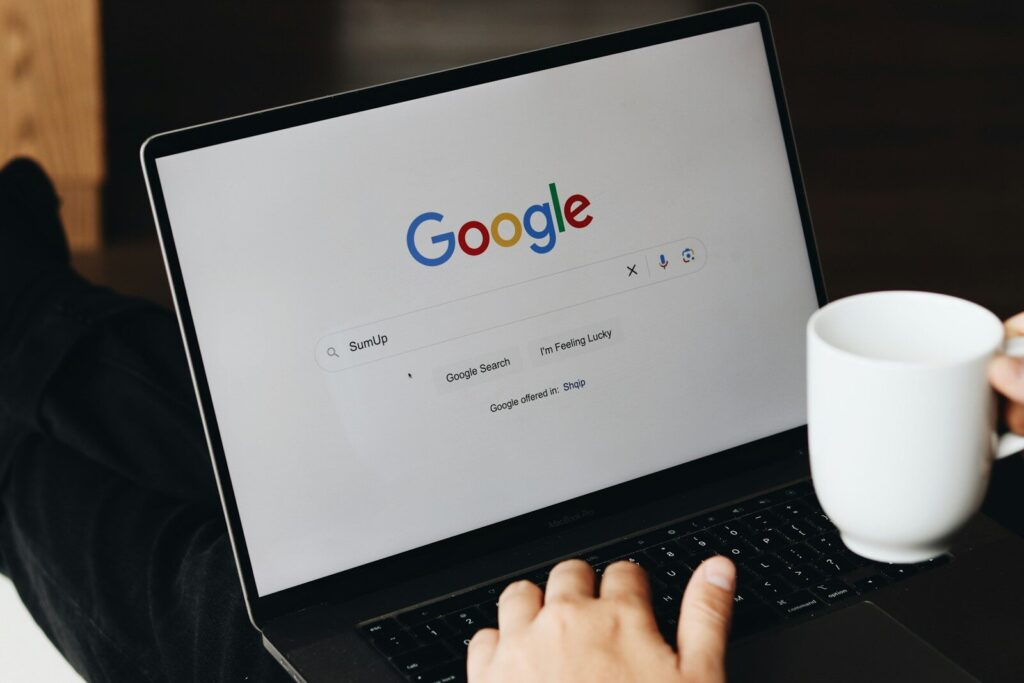 Laptop z otwartą wyszukiwarką i kubkiem kawy na biurku